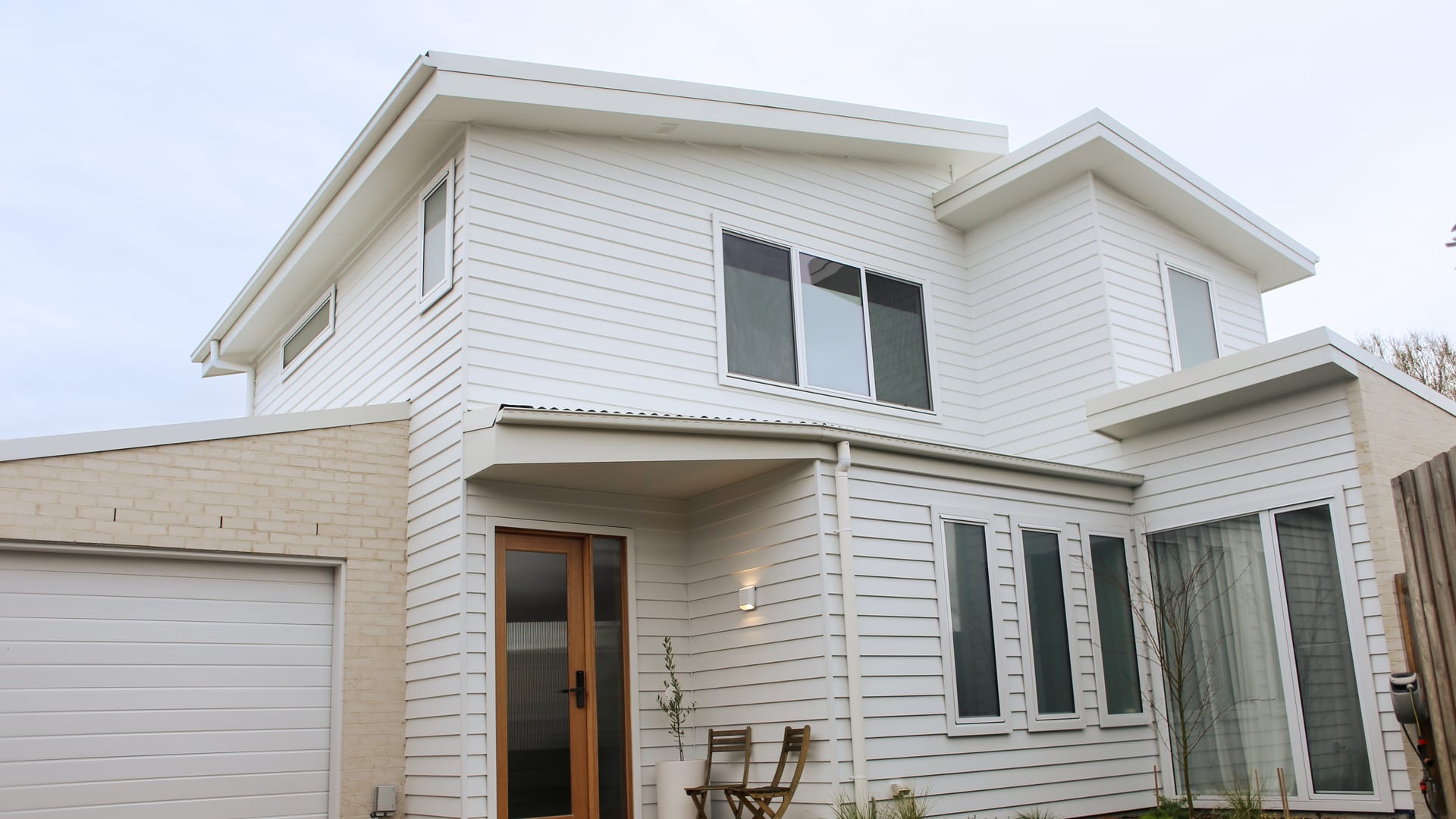 Completed double-storey Bonbeach home in white weatherboard with a timber front door