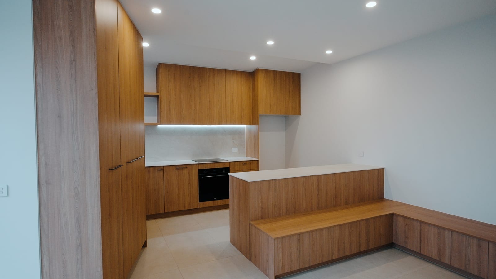 Kitchen in the completed Bonbeach home with oak-tone timber veneer joinery and a porcelain benchtop