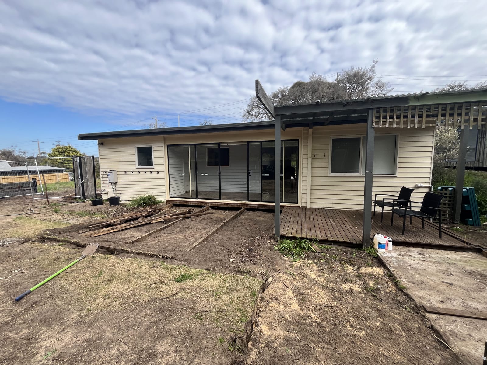 The original cream weatherboard house at David Street before work started, with an old sliding door and a bare dirt yard
