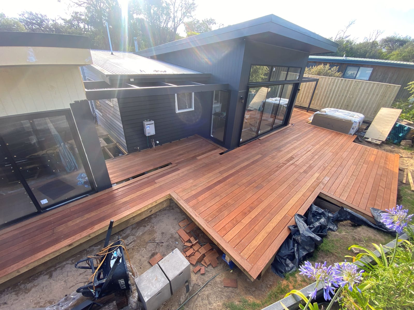 The hardwood deck part-laid against the dark-clad addition, mid-construction