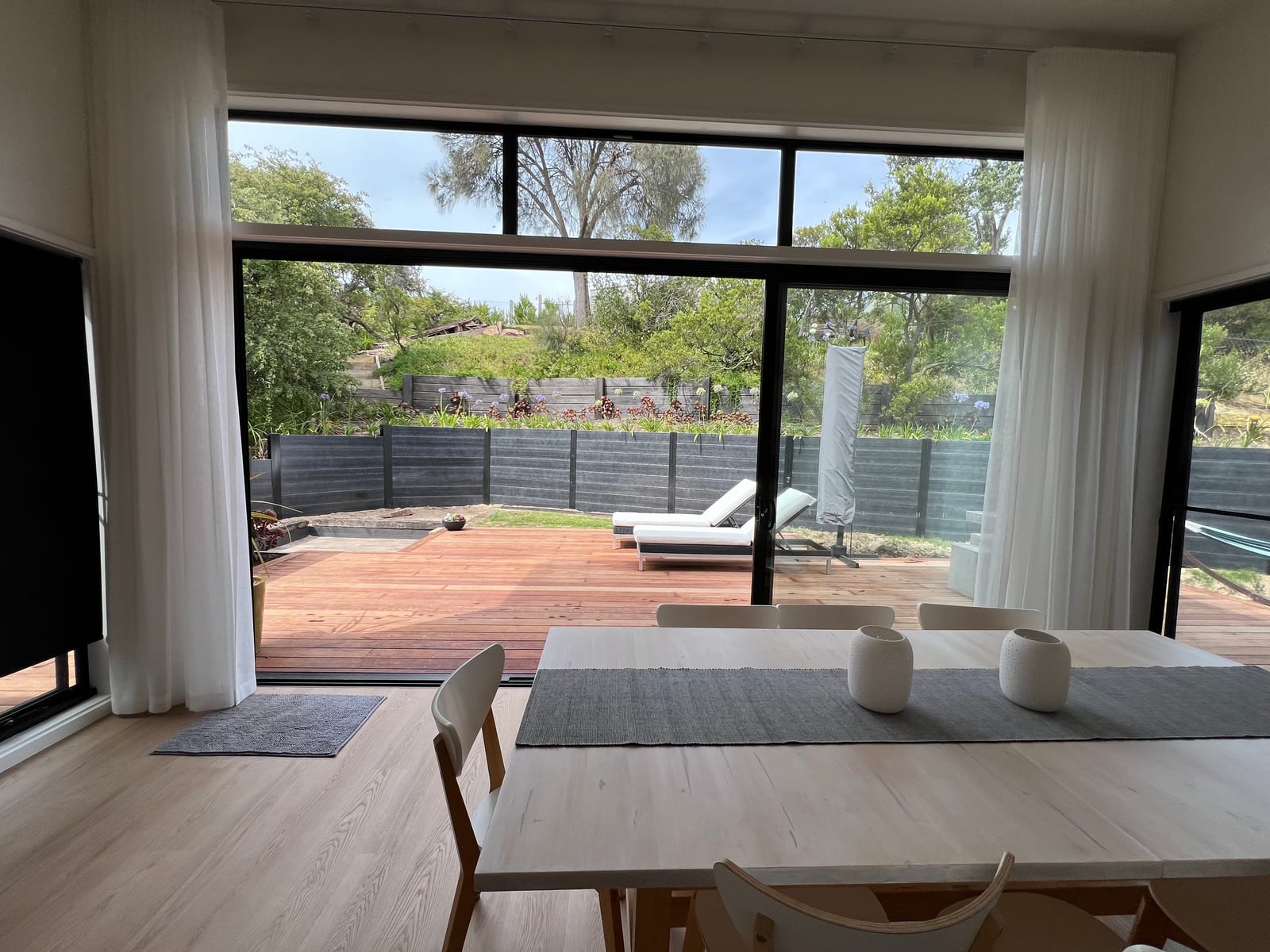 Dining table looking out through full-height sliding doors to the deck and garden