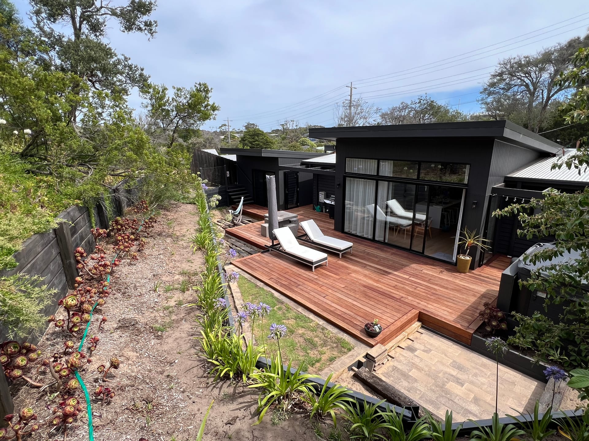 Completed Blairgowrie addition clad in dark timber, with a hardwood deck stepping down to a landscaped coastal garden