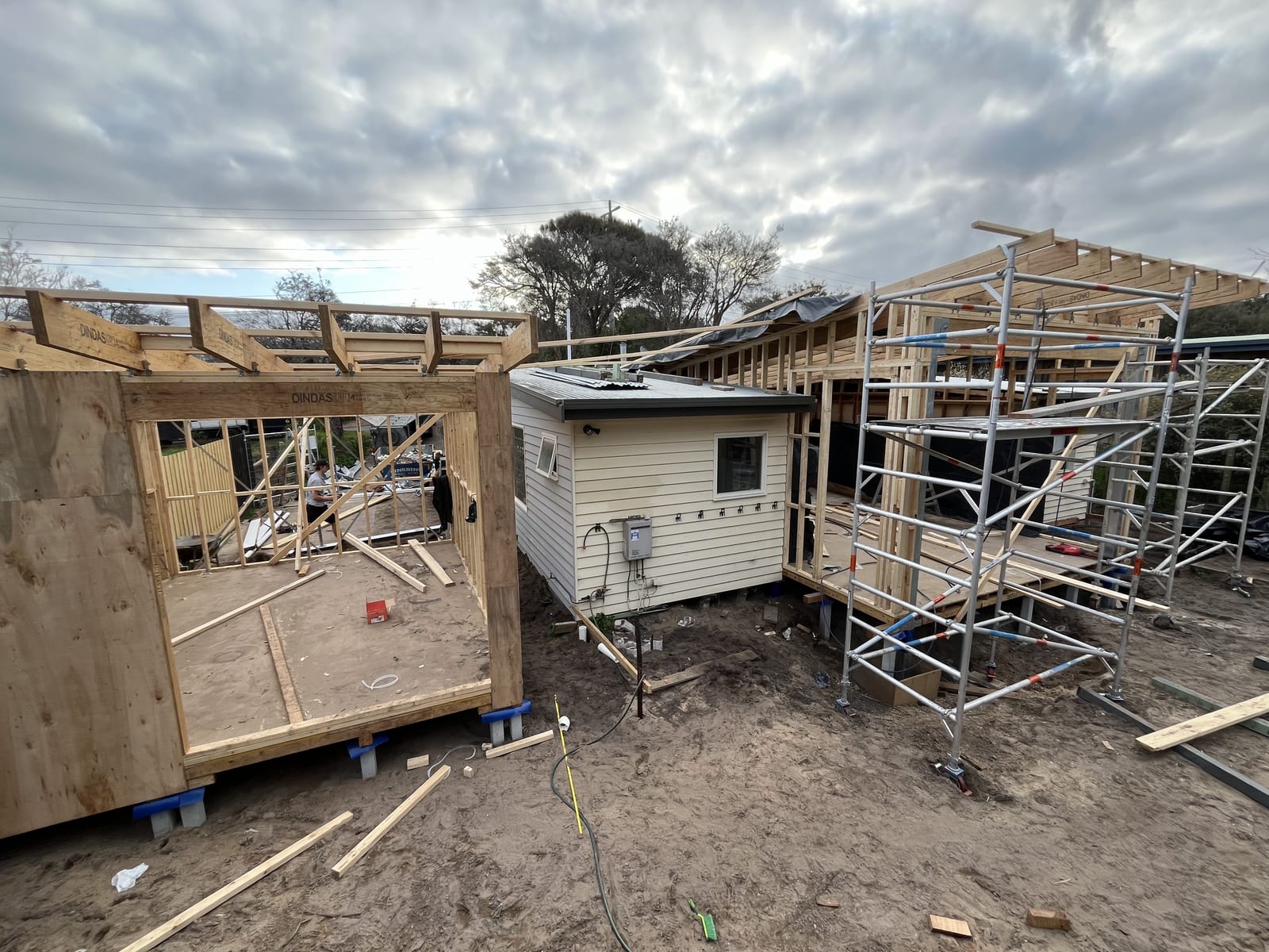 The addition framed and scaffolded, with the original house between the new structures