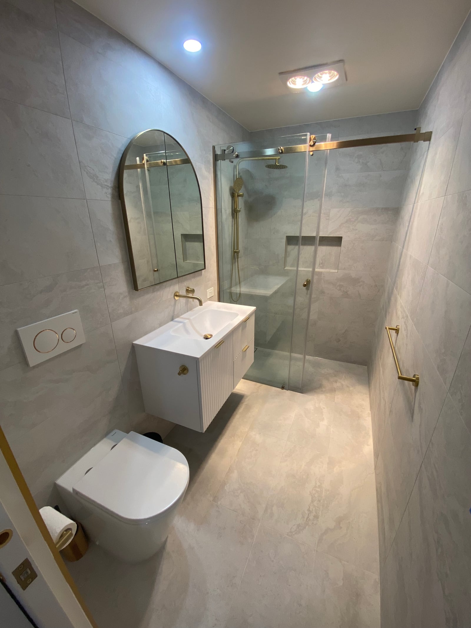 The ensuite shower with a gold-framed screen and a recessed niche