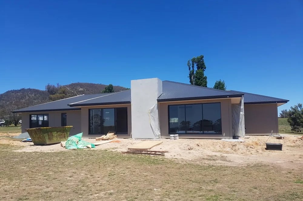 A precast concrete home being rendered, with protective plastic still over the windows and render applied to the panels