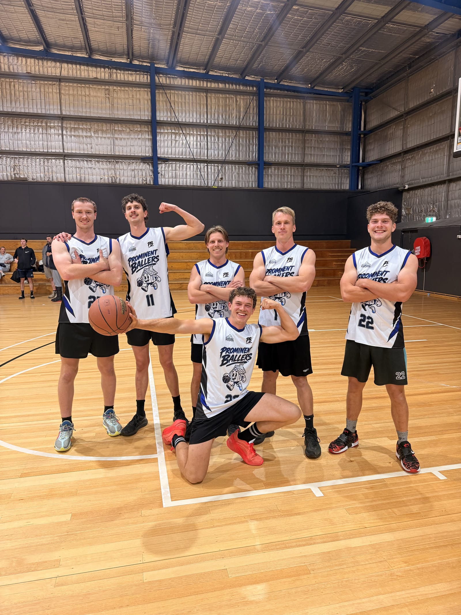 The Prominent Ballers basketball team posing on court in matching Prominent Builders jerseys